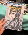  1girl animal_ears art_tools_in_frame artist's_hand_in_frame batman_(series) black_bodysuit black_hair bodysuit breasts brown_hair catsuit catwoman commentary cover_sketch dc_comics english_commentary fake_animal_ears goggles goggles_on_head highres looking_at_viewer marker_(medium) parted_lips photo_(medium) signature stanley_lau traditional_media upper_body whip 