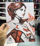  1girl 2017 art_tools_in_frame artist's_hand_in_frame bodysuit breasts clenched_hand closed_mouth commentary dc_comics english_commentary highres long_hair marker_(medium) orange_bodysuit photo_(medium) ponytail red_eyes red_hair red_lips signature solo stanley_lau superman_(series) superman_logo superwoman traditional_media upper_body 