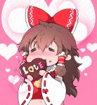  1girl ascot blush bow brown_hair candy chocolate closed_eyes commentary_request detached_sleeves eating facing_viewer food frilled_bow frilled_hair_tubes frills hair_bow hair_tubes hakurei_reimu heart heart-shaped_chocolate heart-shaped_food holding holding_food ichizen_(o_tori) long_hair midriff navel one-hour_drawing_challenge pink_background red_bow ribbon-trimmed_sleeves ribbon_trim solo touhou valentine yellow_ascot 