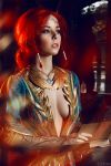  1girl blue_eyes book breasts circlet cosplay costume dress freckles helly_von_valentine_(disharmonica) indoors jewelry long_hair looking_afar makeup medium_breasts necklace no_bra parted_lips pendant photo red_hair robe side_braids solo the_witcher triss_merigold upper_body 