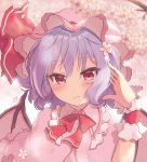  1girl bangs bat_wings beni_kurage blue_hair blush bow bowtie cherry_blossoms commentary_request dress eyebrows_visible_through_hair flower frilled_shirt_collar frills hair_between_eyes hair_flower hair_ornament hand_in_hair hand_up hat hat_ribbon highres light_smile looking_at_viewer mob_cap petals pink_background pink_capelet pink_dress pink_flower pink_headwear red_bow red_eyes red_neckwear red_ribbon remilia_scarlet ribbon short_hair solo touhou upper_body wings wrist_cuffs 