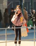  1girl 6+others :| bag black_eyes black_leggings blurry blurry_background brown_hair chips_(food) closed_mouth eating feet_out_of_frame food hair_bun headphones highres holding holding_food leggings lipstick looking_at_viewer makeup multiple_others original outdoors people pole poster_(object) railing red_scarf sam_yang scarf shopping_bag shoulder_bag sidelighting socks standing tote_bag white_socks 