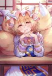  1girl absurdres animal_ears animal_hat blonde_hair blue_tabard blush breast_rest breasts commentary_request dress elbows_on_table fox_ears fox_tail hair_between_eyes hat highres interlocked_fingers jewelry kitsune large_breasts long_sleeves looking_at_viewer masanaga_(tsukasa) medium_hair mob_cap multiple_tails open_mouth own_hands_together red_eyes ring short_hair sitting smile solo tabard table tail touhou wedding_ring white_dress yakumo_ran 