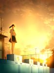  1girl arm_at_side backlighting barefoot black_hair black_skirt building chain-link_fence cloud evening fence highres mamigo original outdoors ponytail pool school_uniform shirt short_sleeves skirt solo standing sunset telephone_pole white_shirt 