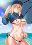  1girl artoria_pendragon_(all) bangs baseball_cap beach_umbrella bikini blonde_hair blue_eyes blue_headwear blue_jacket blush breasts closed_mouth cropped_jacket fate/grand_order fate_(series) hair_between_eyes hat highres jacket kurosawa_(hjkl42332) large_breasts light_smile long_hair looking_at_viewer micro_bikini mysterious_heroine_xx_(foreigner) navel ocean ponytail shrug_(clothing) side-tie_bikini sidelocks solo swimsuit umbrella white_bikini 