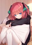 1girl bison_cangshu black_hoodie blue_eyes go-toubun_no_hanayome hair_ornament highres hood hood_down hoodie knees_together_feet_apart knees_up long_sleeves looking_at_viewer nakano_nino parted_lips pillow pink_hair pointing pointing_at_viewer short_hair sitting solo thighhighs two_side_up white_legwear 