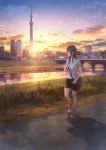  1girl bag black_hair black_shorts bridge building cityscape grass handbag highres lamppost long_hair original red_footwear reflection river scenery shadow sho_(shoichi-kokubun) shoes shorts sidewalk skyscraper sneakers solo stairs sunset walking 