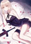  1girl artoria_pendragon_(all) bangs bare_shoulders bed_sheet black_dress blonde_hair blush breasts collarbone dark_excalibur dress fate/stay_night fate_(series) highres leg_garter long_hair looking_at_viewer lying meltymaple on_side pale_skin parted_lips petals pillow saber_alter short_dress small_breasts solo sword thighs weapon yellow_eyes 