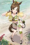  1girl animal_ears beach bikini black_gloves black_sandals blush breasts brown_hair cleavage commentary_request commentary_typo cropped_jacket diagonal_bangs fingerless_gloves gloves green_bikini green_eyes hair_ornament hair_ribbon hairclip highres horse_ears horse_girl horse_tail ines_fujin_(hello_hello_island)_(umamusume) ines_fujin_(umamusume) jacket large_breasts looking_at_viewer multi-strapped_bikini_bottom navel official_alternate_costume official_alternate_hairstyle ponytail ribbon rin_(rin_rinno_) sandals see-through_clothes see-through_jacket shorts single_glove solo swimsuit tail typo umamusume white_shorts yellow_jacket 