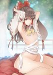  1girl armpits arms_up ascot bow breasts brown_eyes brown_hair detached_sleeves hair_bow hair_tubes hakurei_reimu long_hair looking_at_viewer mouth_hold nipples nude red_bow ribbon-trimmed_sleeves ribbon_trim sarash sidelocks sitting skirt skirt_removed small_breasts solo touhou tousen wide_sleeves yellow_neckwear 