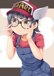  1girl arare_(kantai_collection) bangs baseball_cap bespectacled black_hair blunt_bangs blush brown_eyes character_name clothes_writing commentary_request cosplay cowboy_shot dr._slump eyebrows_visible_through_hair flat_chest frown glasses hands_on_own_face hat highres kantai_collection looking_at_viewer namesake norimaki_arale norimaki_arale_(cosplay) overalls red_headwear red_shirt shirt short_hair short_sleeves sidelocks solo standing two-tone_background winged_hat yasume_yukito 
