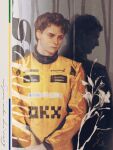  2boys ayrton_senna black_hair brown_eyes brown_hair chanasykine closed_mouth commentary different_reflection formula_one highres long_sleeves male_focus mclaren multiple_boys oscar_piastri own_hands_together racing_suit real_life realistic reflection short_hair 
