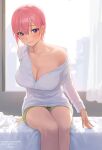  1girl bangs bed_sheet blue_eyes blush breasts cleavage closed_mouth collarbone curtains feet_out_of_frame go-toubun_no_hanayome green_shorts highres indoors large_breasts long_sleeves looking_at_viewer nakano_ichika nhaliz no_bra off_shoulder on_bed pink_hair short_hair short_shorts shorts single_bare_shoulder sitting sitting_on_bed smile solo window 