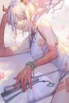  1girl absurdres arknights bangs bare_arms breasts china_dress chinese_clothes dragon_horns dress fan flower highres horns kotatsu_kaya long_hair looking_at_viewer lying nian_(arknights) nian_(unfettered_freedom)_(arknights) open_mouth plum_blossoms purple_eyes silver_hair smile solo 