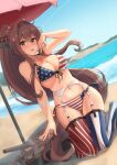 1girl alternate_costume american_flag_bikini ass_visible_through_thighs bangs bare_arms bare_shoulders beach beach_umbrella bikini blush breasts brown_eyes brown_hair cherry_blossoms commentary day flag_print flower front-tie_bikini front-tie_top garter_belt groin hair_flower hair_intakes hair_ornament headgear highres k_jie kantai_collection kneeling large_breasts long_hair looking_at_viewer navel ocean open_mouth outdoors parasol ponytail red_umbrella side-tie_bikini smile solo striped swimsuit symbol_commentary thighhighs turret umbrella very_long_hair water yamato_(kancolle) 