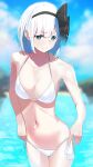  1girl 38_(sanjuuhachi) adjusting_clothes adjusting_swimsuit aqua_eyes bangs bare_shoulders bikini black_hairband black_ribbon blurry blurry_background blush bob_cut breasts bright_pupils cleavage closed_mouth cloud cloudy_sky commentary_request cowboy_shot depth_of_field eyebrows_visible_through_hair furrowed_brow hair_ribbon hairband highres konpaku_youmu lake looking_at_viewer medium_breasts outdoors ribbon short_hair silver_hair sky solo standing stomach swimsuit touhou water white_bikini white_pupils 