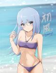  1girl absurdres bangs beach bespectacled bikini blue_hair blunt_bangs breasts character_name cowboy_shot eyes_visible_through_hair glasses green_eyes halter_top halterneck hatsukaze_(kancolle) highres honma_(honmatomohiro) kantai_collection looking_at_viewer medium_breasts purple_bikini solo swimsuit twitter_username white_hair 