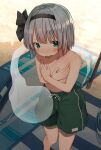  1girl absurdres beach beach_towel blush commentary covering covering_breasts crossdressing flat_chest hairband highres konpaku_youmu looking_at_viewer male_swimwear male_swimwear_challenge mamemochi short_hair silver_hair solo sweatdrop swim_trunks topless touhou towel wavy_mouth 