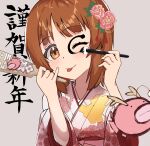  1girl ;p absurdres anglerfish brown_eyes brown_hair calligraphy_brush commentary emblem facepaint fish floral_print flower girls_und_panzer grey_background hagoita hair_flower hair_ornament hanetsuki head_tilt highres holding holding_brush japanese_clothes kimono lazurite_(user_8870367) new_year nishizumi_miho one_eye_closed paddle paintbrush pink_flower pink_kimono print_kimono short_hair solo text_background tongue tongue_out translated 