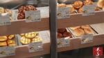  bakery bread display display_case food food_focus highres indoors kaneko_ryou no_humans original pastry price_tag shop still_life 