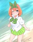  1girl bangs beach blue_eyes blush bow breasts collared_shirt commentary_request day dress_shirt eyebrows_behind_hair feet_out_of_frame go-toubun_no_hanayome green_bow green_ribbon green_skirt grin hair_between_eyes highres kujou_karasuma looking_at_viewer medium_breasts nakano_yotsuba one_eye_closed outdoors pleated_skirt ribbon sand shirt short_sleeves signature skirt smile solo water white_shirt 