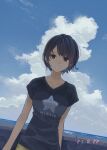  1girl black_hair brown_eyes cloud commentary dutch_angle highres looking_at_viewer minamito ocean original outdoors photo_date_watermark shirt short_hair sky smile solo t-shirt 