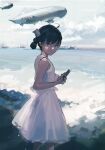  1girl absurdres aircraft bare_arms beach black_eyes black_hair chromatic_aberration closed_mouth cloud cloudy_sky commentary dirigible dress english_commentary feet_out_of_frame from_side hair_bun highres holding holding_phone looking_at_viewer looking_to_the_side ocean original outdoors phone ship sky sleeveless sleeveless_dress smile solo watercraft white_dress zygocactus 