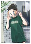  1girl absurdres black_headwear blonde_hair blue_eyes cellphone earrings fang green_shirt hat_ornament highres holding holding_phone hoop_earrings jewelry knit_hat ko_tachi1104 nail_polish original phone red_nails shirt short_hair shorts skin_fang smartphone standing 