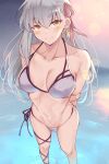  1girl arms_behind_back bangs bare_shoulders bikini blue_eyes blush breasts cleavage collarbone earrings eyebrows_visible_through_hair fate/grand_order fate_(series) hair_ribbon highres jewelry kama_(fate) large_breasts long_hair looking_at_viewer matcha7611 navel ocean partially_submerged red_eyes ribbon silver_hair smile standing swimsuit thighs white_bikini 