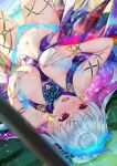  1girl bangs bare_shoulders blue_fire blush body_markings bracelet breasts covering covering_breasts earrings fate/grand_order fate_(series) fire flower hair_flower hair_ornament hair_ribbon highres jewelry kama_(fate) kama_(swimsuit_avenger)_(fate) large_breasts long_hair looking_to_the_side lotus lying multicolored_hair on_back open_mouth purple_hair red_eyes revealing_clothes ribbon silver_hair solar_(happymonk) solo sparkle star_(sky) star_(symbol) star_earrings thighs two-tone_hair 
