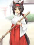  1girl ahoge animal_ears black_hair breasts broom brown_eyes commentary_request feet_out_of_frame hakama headband highres horse_ears horse_girl horse_tail japanese_clothes kimono logotype_(umamusume) looking_at_viewer low_ponytail medium_breasts miko pataneet ponytail red_hakama red_headband smile solo standing tail torii umamusume white_kimono 