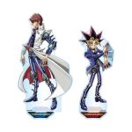  2boys acrylic_stand_(medium) belt belt_collar black_hair blonde_hair brown_hair coat collar colored_bangs commentary_request duel_disk highres jacket kaiba_seto knee_pads looking_at_viewer looking_to_the_side male_focus multicolored_hair multiple_boys official_art pants pink_hair takahashi_kazuki two-sided_fabric white_background white_coat yami_yugi yu-gi-oh! 