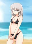  1girl bangs beach bikini black_bikini blue_eyes blue_sky blurry blurry_background breasts cleavage closed_mouth commentary cowboy_shot day eyebrows_visible_through_hair gam girls_und_panzer halterneck highres horizon interlocked_fingers itsumi_erika light_blush light_frown looking_at_viewer medium_breasts medium_hair navel ocean outdoors own_hands_together silver_hair sky solo standing swimsuit v_arms 