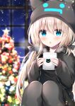  1girl :o animal_ears animal_hood asymmetrical_hair bangs black_jacket black_legwear blonde_hair blue_eyes blurry blurry_background blush christmas christmas_ornaments christmas_tree commentary_request cup depth_of_field eyebrows_visible_through_hair fake_animal_ears feet_out_of_frame hair_between_eyes holding holding_cup hood hood_up hooded_jacket jacket knees_up long_sleeves low_twintails mug original pantyhose parted_lips puffy_long_sleeves puffy_sleeves signature sitting sleeves_past_wrists solo tia-chan twintails uchuuneko window 