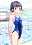  1girl absurdres arms_behind_back black_hair blue_swimsuit blurry blurry_background breasts brown_eyes clothes_writing competition_swimsuit cowboy_shot highres lane_line logo looking_at_viewer multicolored_clothes multicolored_swimsuit one-piece_swimsuit original ponytail pool short_hair short_ponytail small_breasts smile solo standing string_of_flags swimsuit takafumi 