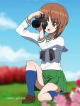  1girl artist_name bangs blue_legwear blue_sky blurry blurry_background blurry_foreground camera cloud cloudy_sky commentary_request dated depth_of_field eyebrows_visible_through_hair girls_und_panzer grass highres holding holding_camera looking_to_the_side naotosi nishizumi_miho one_knee open_mouth outdoors short_hair single-lens_reflex_camera sky smile solo taking_picture 