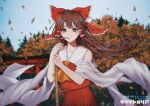  1girl artist_request autumn_leaves bamboo_broom bare_shoulders blush bow broom brown_eyes brown_hair day detached_sleeves floating_hair hair_tubes hakurei_reimu highres leaf long_hair maple_leaf motion_blur outdoors red_bow sky smile solo touhou upper_body wide_sleeves 