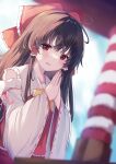  1girl :d absurdres alternate_neckwear bare_shoulders blurry blurry_background bow bowtie brown_hair day depth_of_field detached_sleeves dutch_angle eyebrows_behind_hair hair_bow hair_tubes hakurei_reimu highres kogalashi long_hair outdoors own_hands_together palms_together parted_lips red_eyes smile solo touhou wide_sleeves yellow_bow yellow_bowtie 