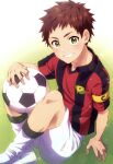  1boy absurdres ball character_request commentary_request copyright_request crossed_legs day green_eyes highres holding holding_ball kanamaru_yuuki looking_at_viewer male_focus outdoors red_hair short_hair shorts shou_oota soccer_ball solo teeth uniform victory_kickoff!! 