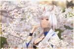  1girl akizuki_(17769498) animal_ear_fluff azur_lane blue_eyes blurry blurry_background breasts chromatic_aberration cleavage eyeliner flower from_side highres japanese_clothes kaga_(azur_lane) kimono large_breasts looking_at_viewer looking_to_the_side makeup red_eyeliner short_hair solo upper_body white_flower white_hair white_kimono 